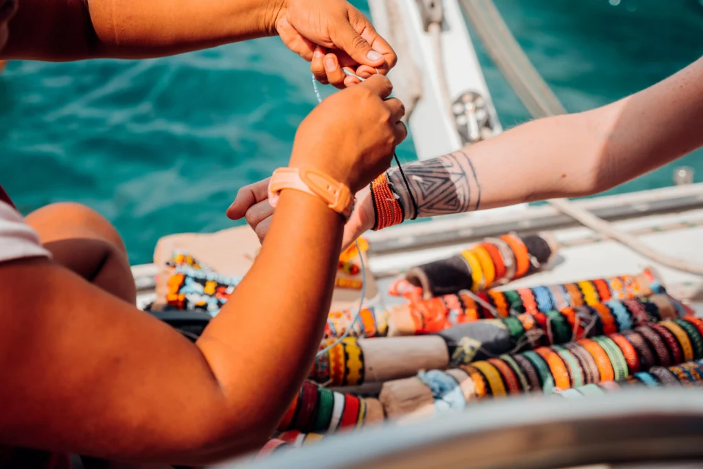 Guna Woman puts traditional guna bracelet (wuini) in woman wrist, San Blas-min
